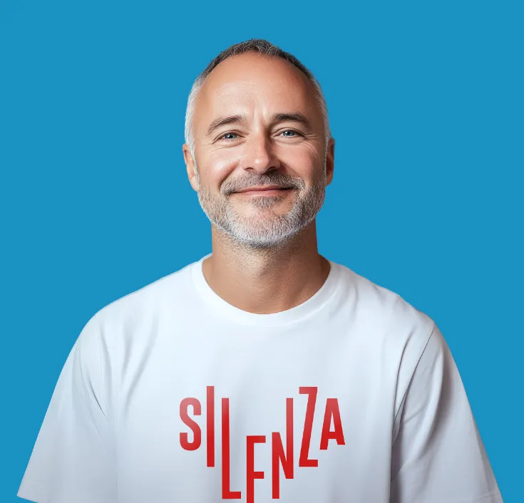 Porträt eines lächelnden Mannes mit grauem Bart im weißen Silenza-T-Shirt vor blauem Hintergrund